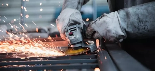 Worker using a tool operating on steel