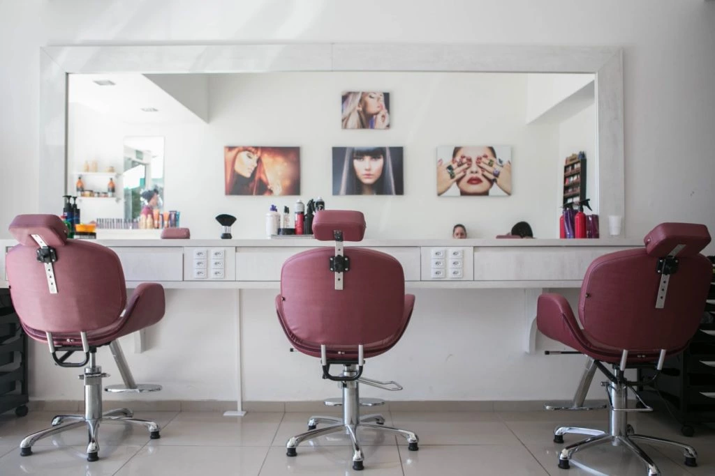 Image of a beauty salon with three chairs visible for clients and a table with beauty products