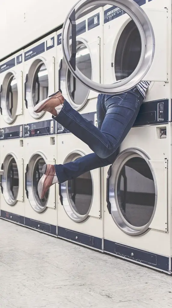 Humorous image of a woman stuck in the washing machine, her legs only out