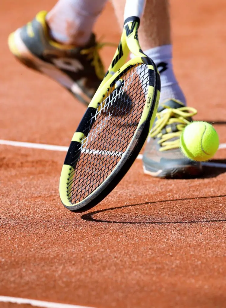 Image of a tennis player, zoomed in tennis court, tennis shoes and ball are visible