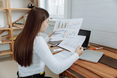 Image of a businesswoman looking at sales statistics on paper